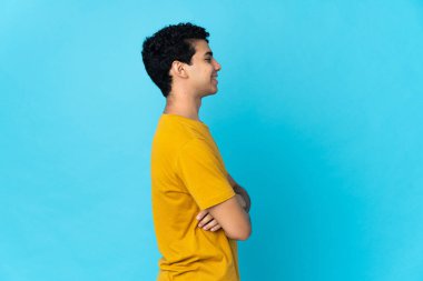 Genç Venezuelalı adam mavi arka planda yan pozisyonda izole edildi.