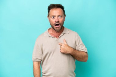 Mavi arka planda soyutlanmış orta yaşlı beyaz bir adam kendini işaret ediyor.