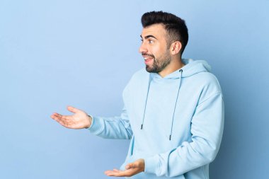 Tarafsız mavi arka plan üzerinde beyaz bir adam sürpriz bir ifadeyle bakarken