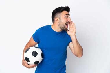 Yakışıklı genç futbolcu, izole olmuş duvarın üzerinden ağzı açık bağırıyor.