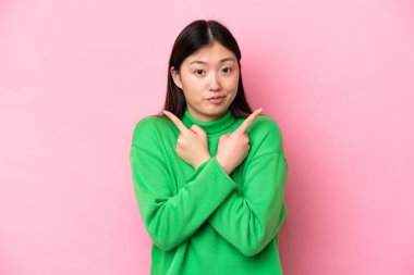 Pembe arka planda izole edilmiş genç Çinli kadın, yan taraftakilerin şüphelerine işaret ediyor.