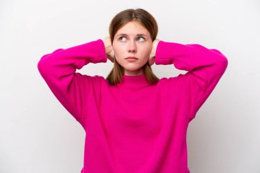 Beyaz arka planda izole edilmiş genç bir İngiliz kadın hayal kırıklığına uğramış ve kulaklarını kapatmış.