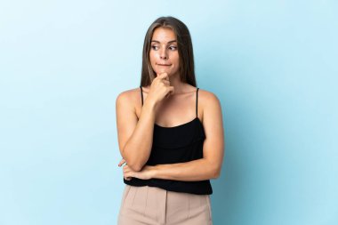 Genç Uruguaylı kadın mavi arka planda izole edilmiş. Şüpheleri ve düşünceleri var.