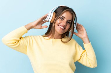 Genç Uruguaylı kadın mavi arka planda müzik dinliyor.