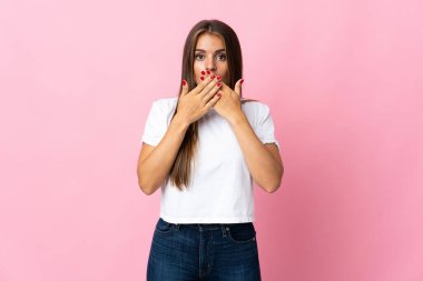 Genç Uruguaylı kadın pembe arka planda izole edilmiş, ağzı elleriyle kapatılmış.