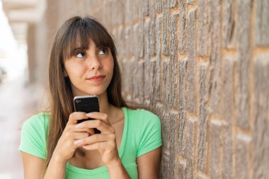 Dışarıda cep telefonu kullanan genç bir kadın.