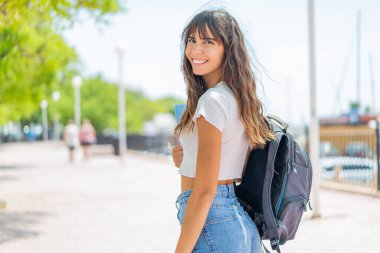 Dışarıda elinde mutlu bir ifadeyle bir defter tutan genç bir kadın.