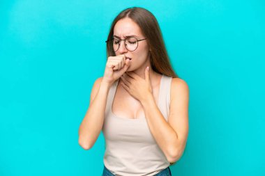 Mavi arka planda izole edilmiş genç beyaz kadın çok öksürüyor.