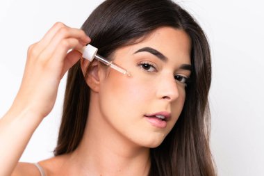 Beyaz arka planda izole edilmiş genç Brezilyalı bir kadın elinde bir serum tutuyor. Portreyi kapat