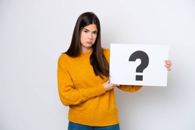 Genç Brezilyalı bir kadın beyaz arka planda izole edilmiş. Elinde üzerinde üzgün bir ifade olan soru işareti olan bir levha var.