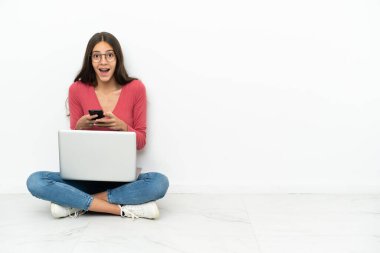 Dizüstü bilgisayarıyla yerde oturan genç Fransız kız şaşırdı ve bir mesaj gönderiyor.