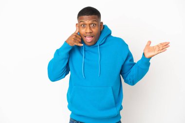 Beyaz arka planda izole edilmiş genç latin adam telefon jesti yapıyor ve şüphe ediyor