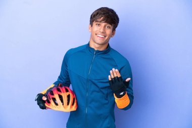 Mor arka planda izole edilmiş genç bir beyaz adam bizimle gelmesi için davet ediyor. Gelmene sevindim.