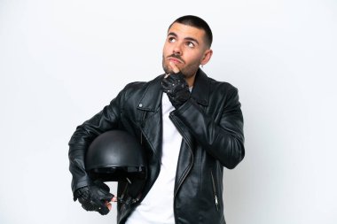 Beyaz arka planda izole edilmiş motosiklet kasklı beyaz bir adam yukarı bakarken şüpheleri var.