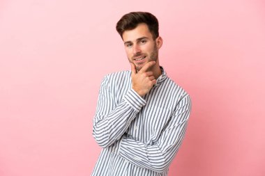 Beyaz tenli yakışıklı bir adam pembe arka planda izole edilmiş mutlu ve gülümsüyor.