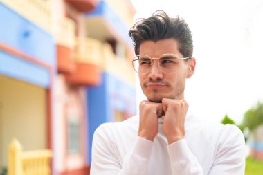 Dışarıda gözlüklü ve yorgun beyaz bir adam var.