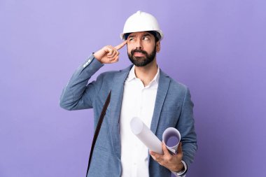 Miğferli genç bir mimar. Mor arka planının planlarını tutuyor. Şüpheleri ve düşünceleri var.