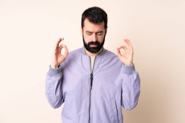 Sakallı, ceketli, soyutlanmış, zen pozlu beyaz bir adam.