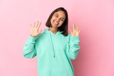 Pembe arka planda izole edilmiş genç Latin kadın parmaklarıyla ona kadar sayıyor.