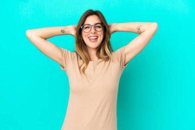 Mavi arka planda izole edilmiş genç beyaz kadın gülüyor.