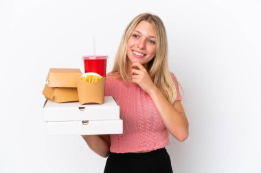 Mavi arka planda yağlı yiyecekler tutan beyaz bir kadın. Yan tarafa bakıyor ve gülümsüyor.