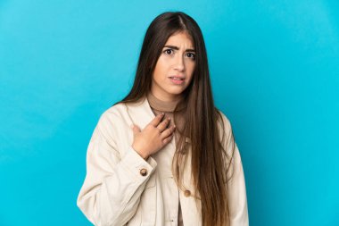 Mavi arka planda izole edilmiş genç beyaz kadın kendini işaret ediyor.