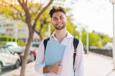 Açık havada gülümseyen yakışıklı bir öğrenci.