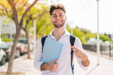 Yüzünde sürpriz bir ifade olan genç ve yakışıklı bir öğrenci.
