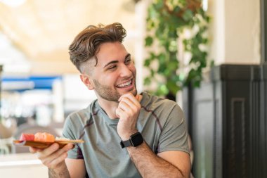 Sashimi 'yi açık havada tutan genç yakışıklı bir adam bir fikir üretiyor ve ona bakıyor.