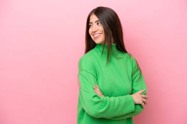 Pembe arka planda soyutlanmış, kolları bağlı ve mutlu, beyaz bir kadın.