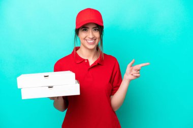 İş üniformalı bir pizzacı kadın mavi arka planda izole edilmiş pizza kutularını topluyor.