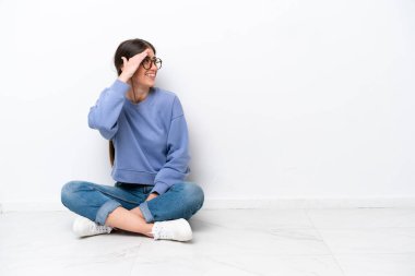 Beyaz arka planda izole bir şekilde yerde oturan genç beyaz kadın bir şeyin farkına vardı ve çözüme niyetlendi.