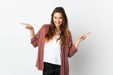 Beyaz arka planda izole edilmiş genç İrlandalı kadın parmak uçlarını işaret ediyor ve mutlu