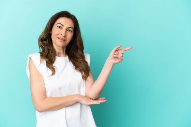 Mavi arka planda izole edilmiş orta yaşlı, beyaz bir kadın.