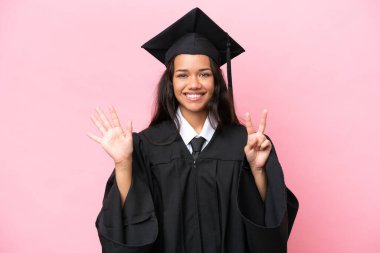 Kolombiyalı genç bir üniversite mezunu. Pembe arka planda tecrit edilmiş. Parmaklarıyla yediyi sayıyor.