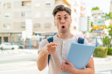 Dışarıdaki yakışıklı genç adam şaşırmış ve ön tarafı işaret ediyor.