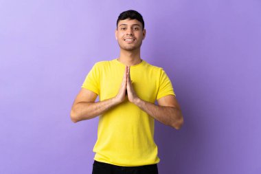 Mor arka planda izole genç Kolombiyalı adam avuç içlerini bir arada tutuyor. İnsan bir şey ister.