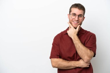 Beyaz arka planda izole edilmiş genç beyaz adam mutlu ve gülümsüyor.