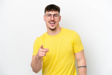 Beyaz arka planda izole edilmiş beyaz, yakışıklı genç adam şaşırmış ve ön tarafı işaret ediyor.