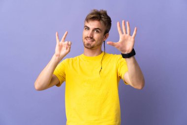 Mor arka planda izole edilmiş yakışıklı sarışın adam yediyi parmaklarıyla saydı.