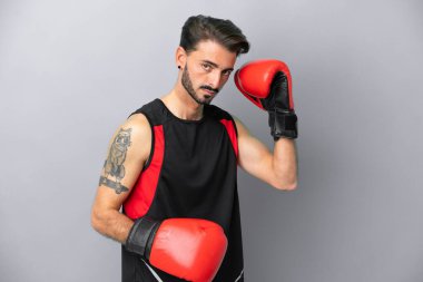 Gri arka planda boks eldivenli, beyaz, genç bir adam.