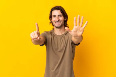 Sarı arka planda izole edilmiş genç yakışıklı altı parmaklı sayıyor.