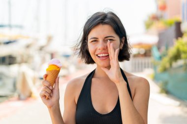 Açık havada kornet dondurması olan genç, güzel Bulgar kadın ağzı açık bağırıyor.