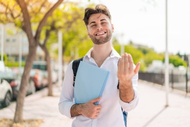 Açık havada genç yakışıklı bir öğrenci benimle gelmesi için davet ediyor. Gelmene sevindim.