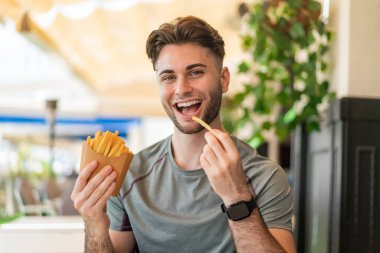 Genç yakışıklı adam patates kızartması alıyor.