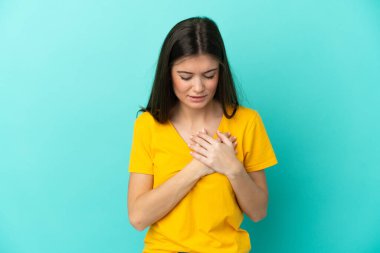 Mavi arka planda izole edilmiş beyaz bir kadın. Kalbinde ağrı var.