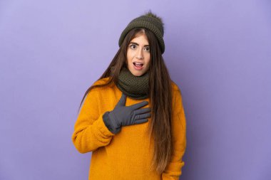 Mor arka planda izole edilmiş beyaz şapkalı genç kız sağa bakarken şaşırdı ve şok oldu.