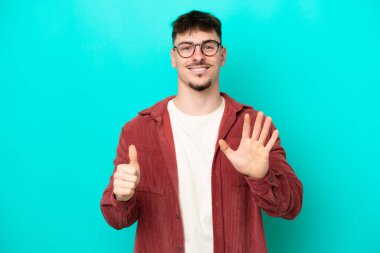 Beyaz tenli yakışıklı adam mavi arka planda izole edilmiş. Parmakları olan altı kişi saydım.