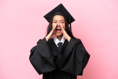 Üniversiteden mezun genç bir Kolombiyalı kadın pembe arka planda izole edilmiş bağırıyor ve bir şeyler söylüyor.