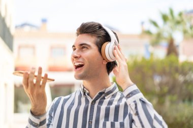 Genç yakışıklı adam müzik dinliyor ve şarkı söylüyor.